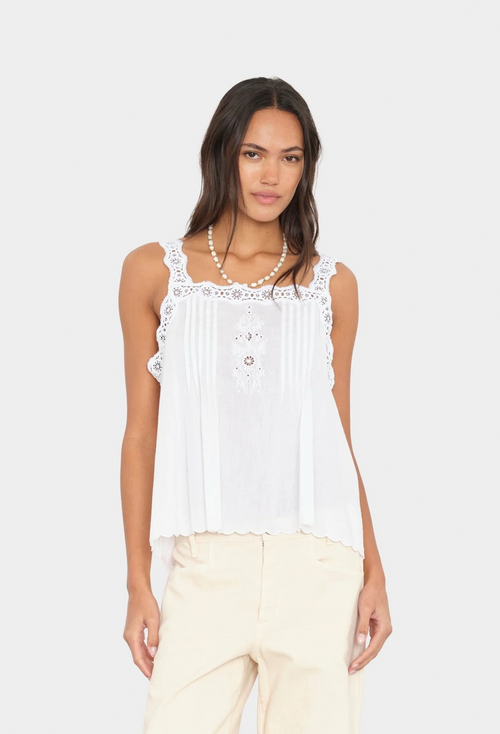 Woman wearing a white sleeveless top with lace details on a plain background