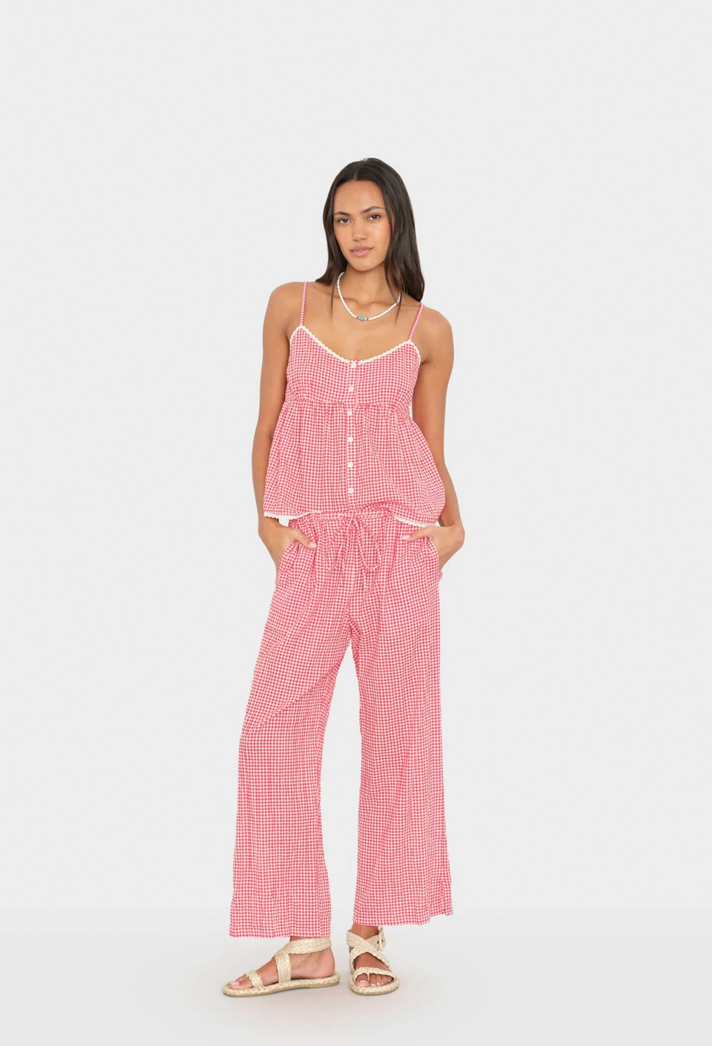 Woman wearing a pink checkered top and pants on a white background