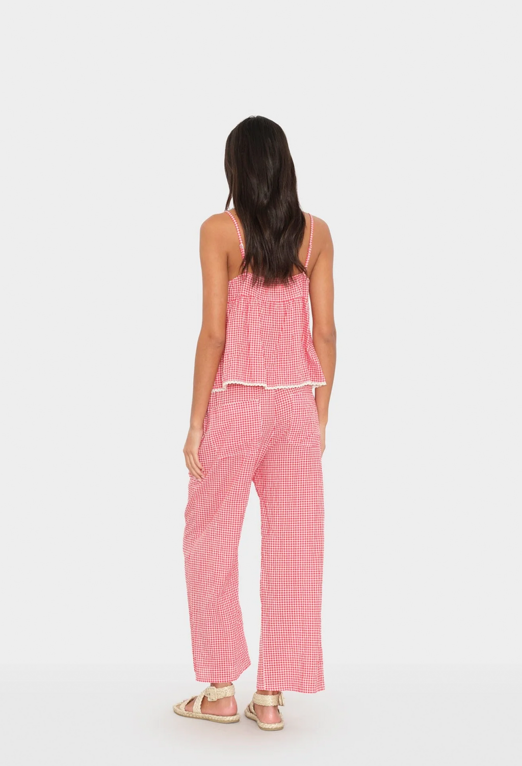 Woman wearing a pink checkered outfit on a white background