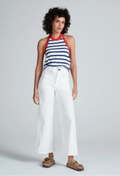 Woman wearing a striped top and white pants on a plain background
