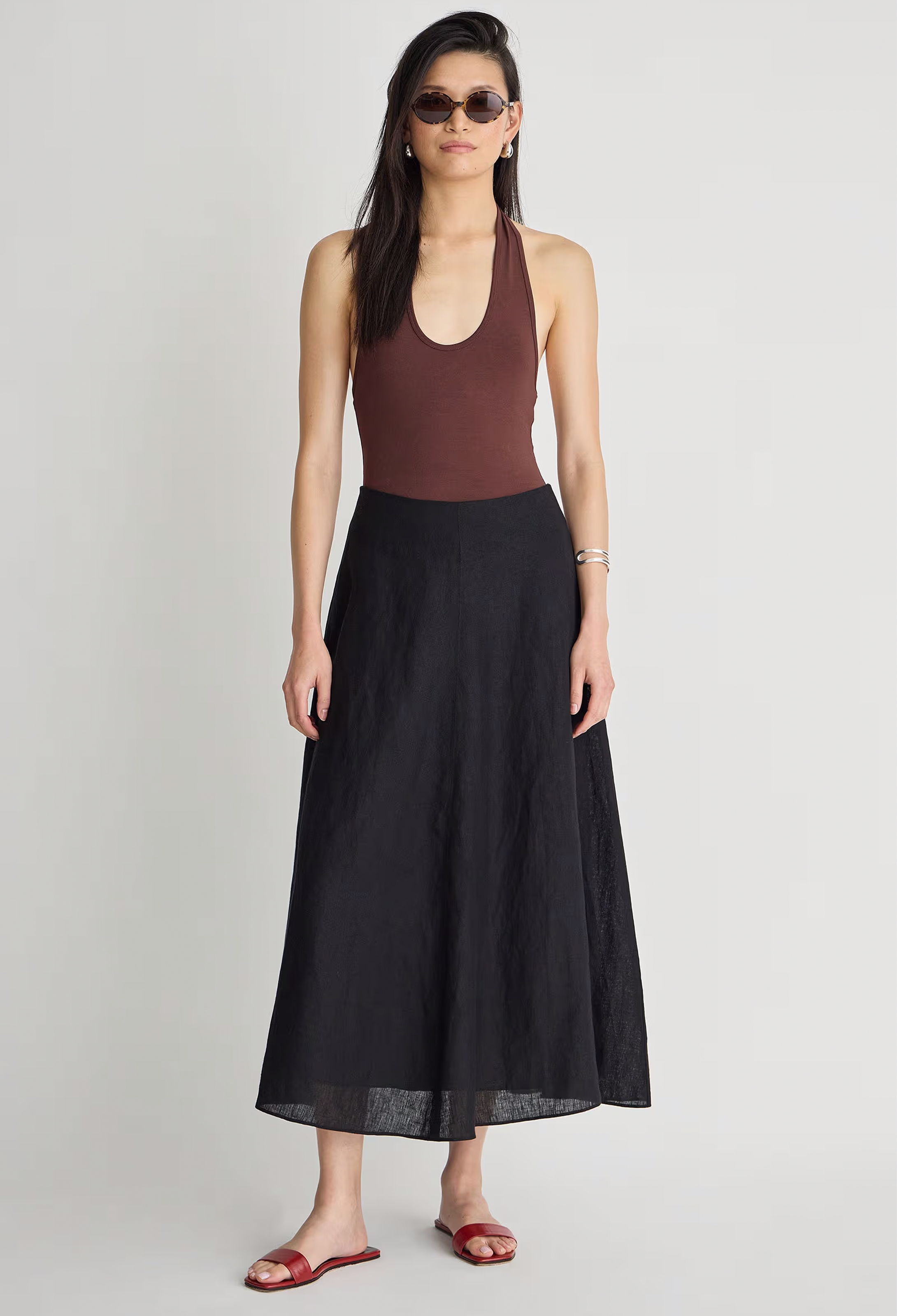 Woman wearing a brown halter top and black long skirt on a white background