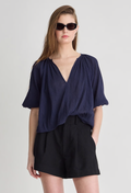 Woman wearing a navy blue top and black shorts on a light gray background