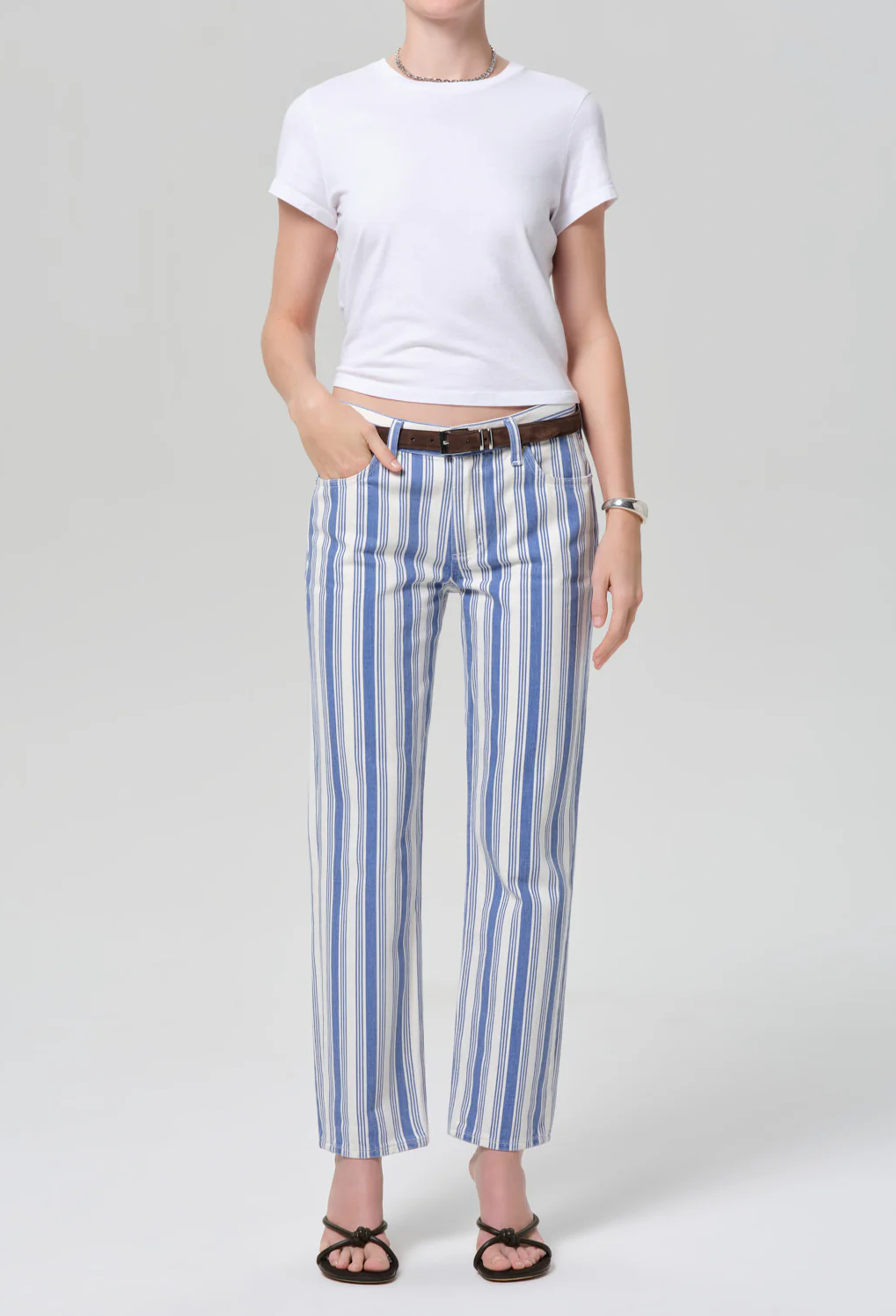 Person wearing a white t-shirt and blue striped pants on a plain background