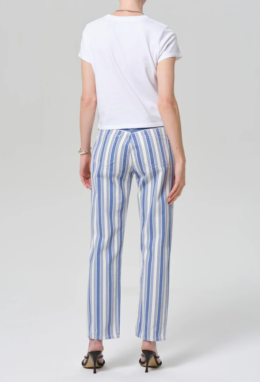 Person wearing a white t-shirt and blue striped pants on a plain background