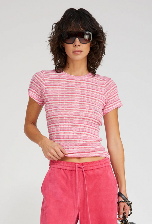 Woman wearing a pink striped shirt and pink pants with sunglasses on a white background