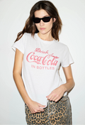 Woman wearing a white t-shirt with red text and leopard print pants on a plain background