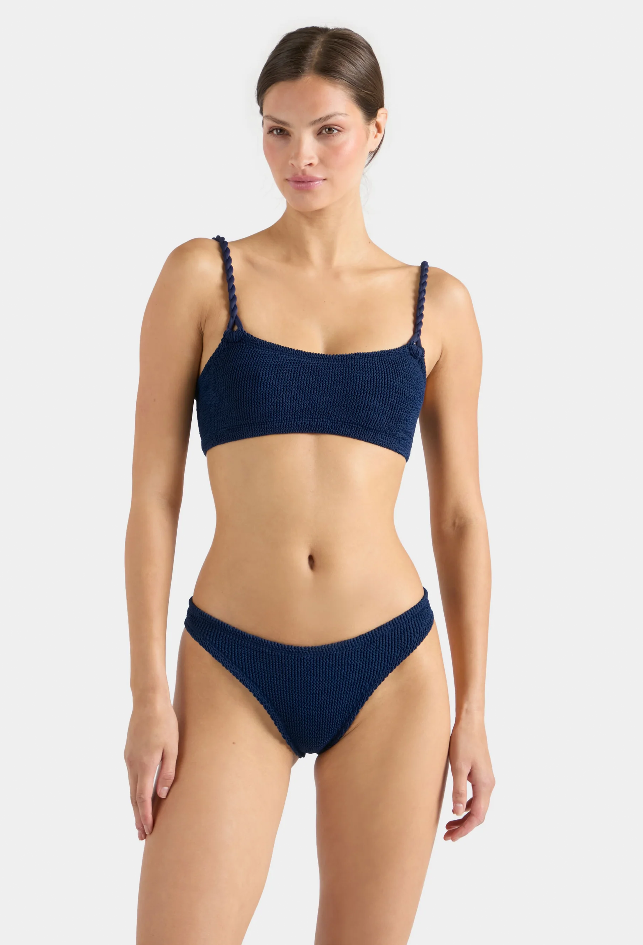 Woman wearing a navy blue bikini on a white background