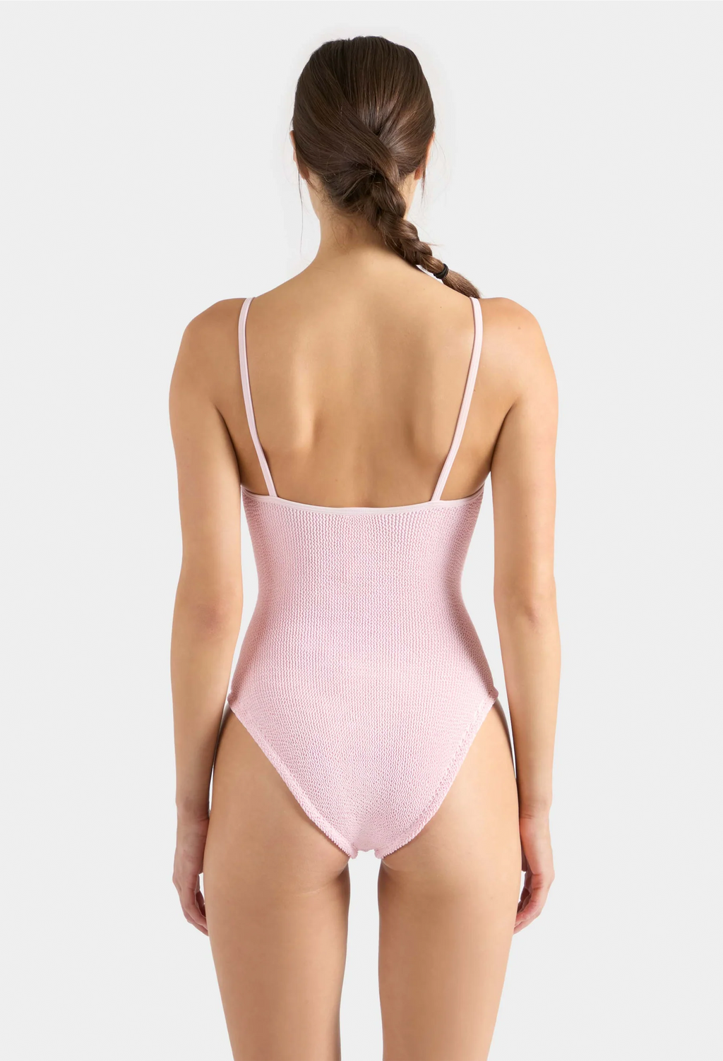 Woman wearing a pink swimsuit with thin straps on a white background