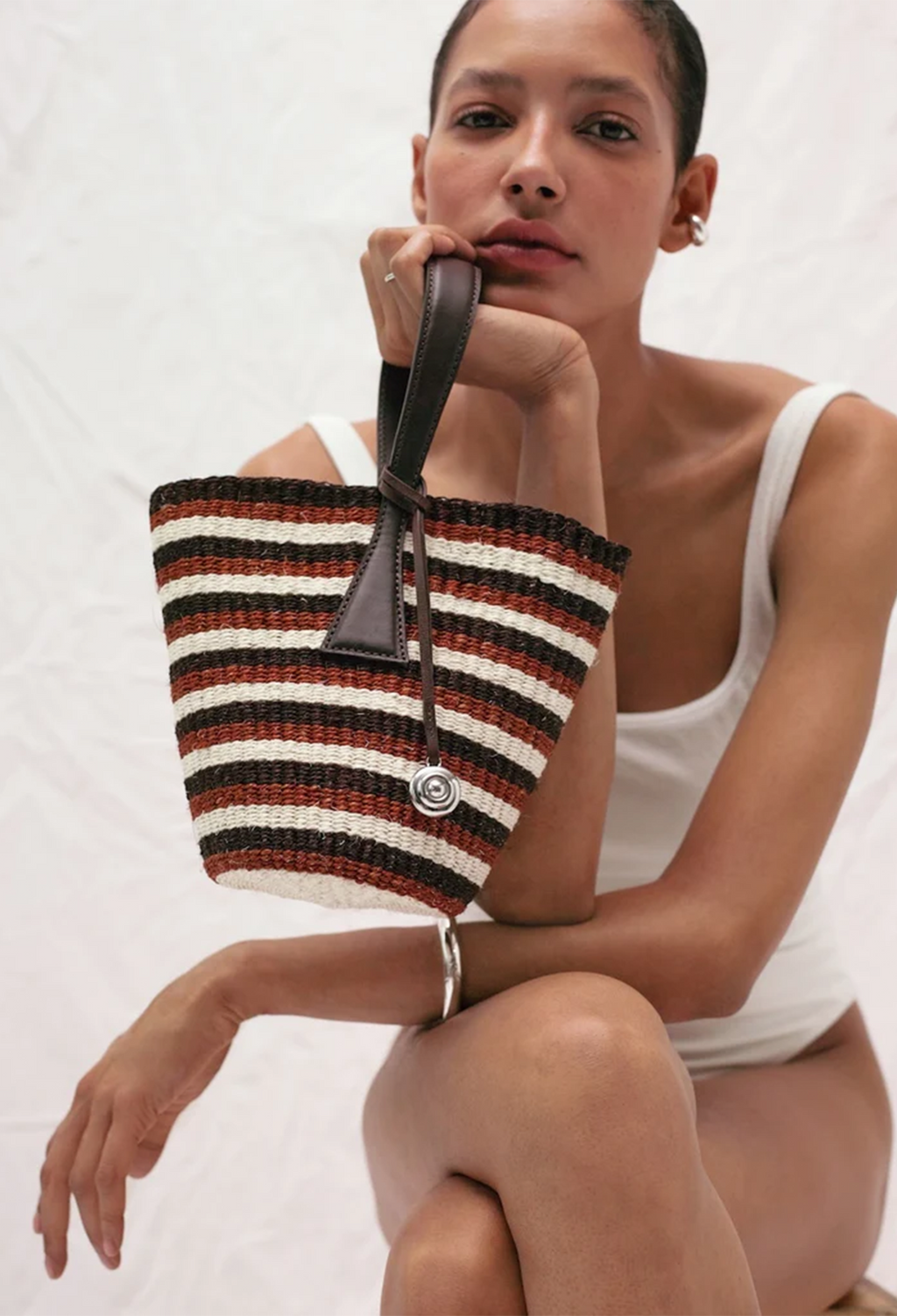 Woman holding a striped woven bag against a white background