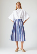 Woman wearing a white blouse and blue striped skirt on a plain background