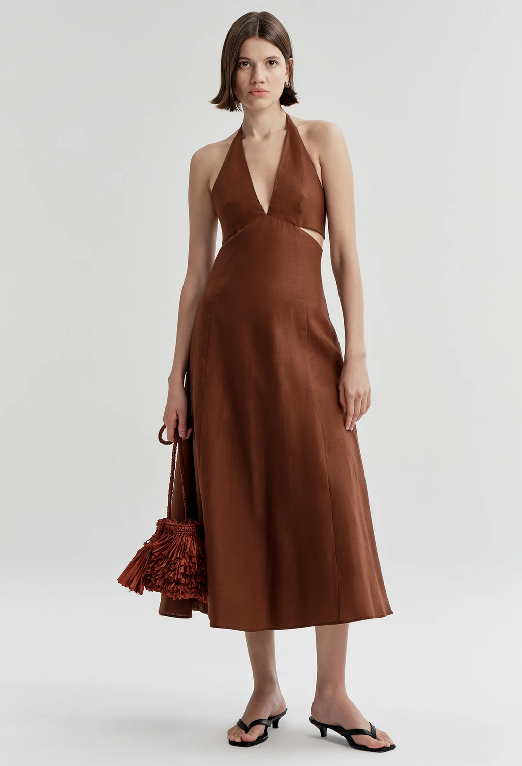 Woman wearing a brown halter neck dress on a white background