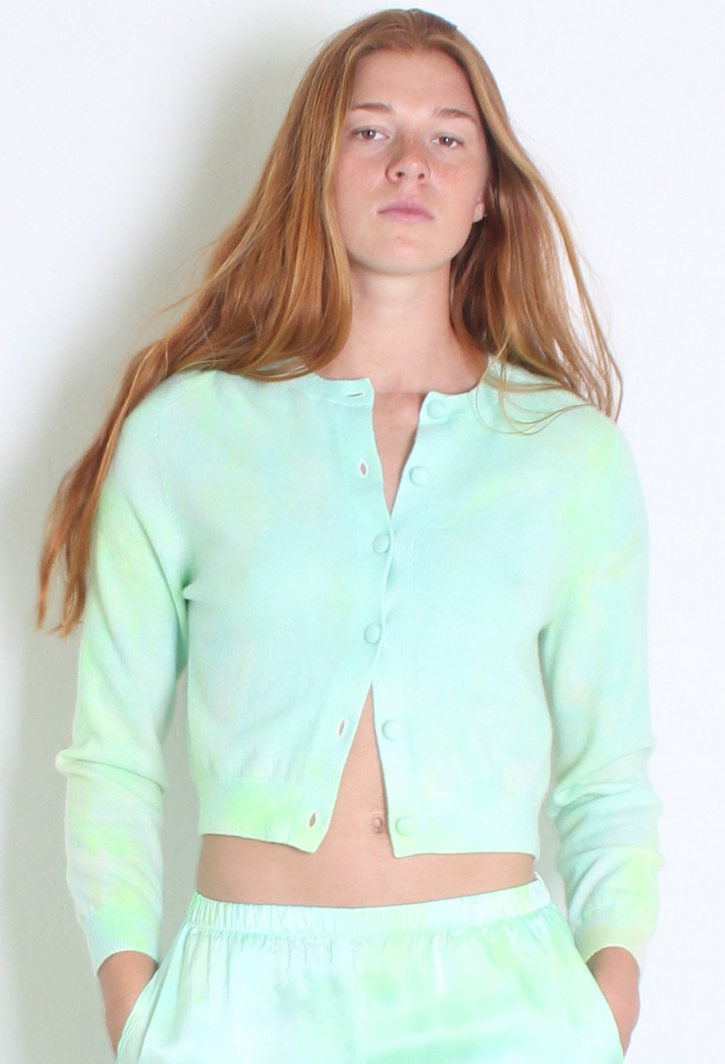 Woman wearing a light green tie-dye outfit against a plain background
