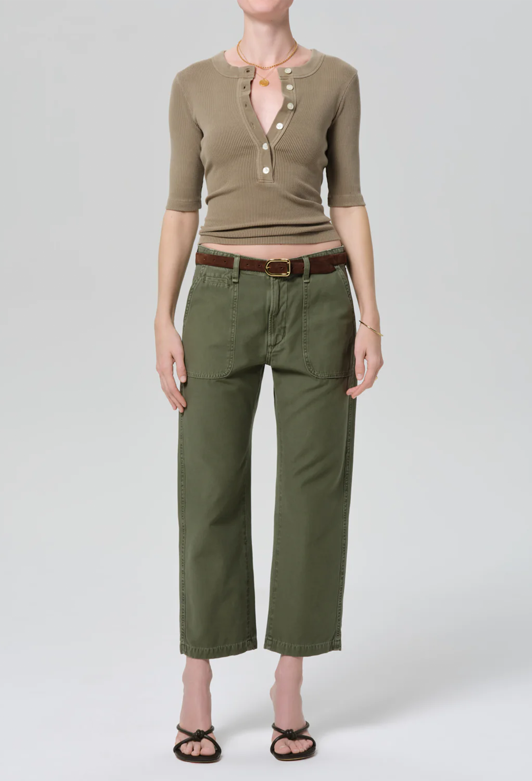 Person wearing a green top and pants with a belt on a white background