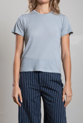 Person wearing a light blue t-shirt and navy pinstripe pants on a neutral background