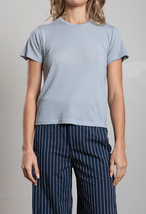 Person wearing a light blue t-shirt and navy pinstripe pants on a neutral background