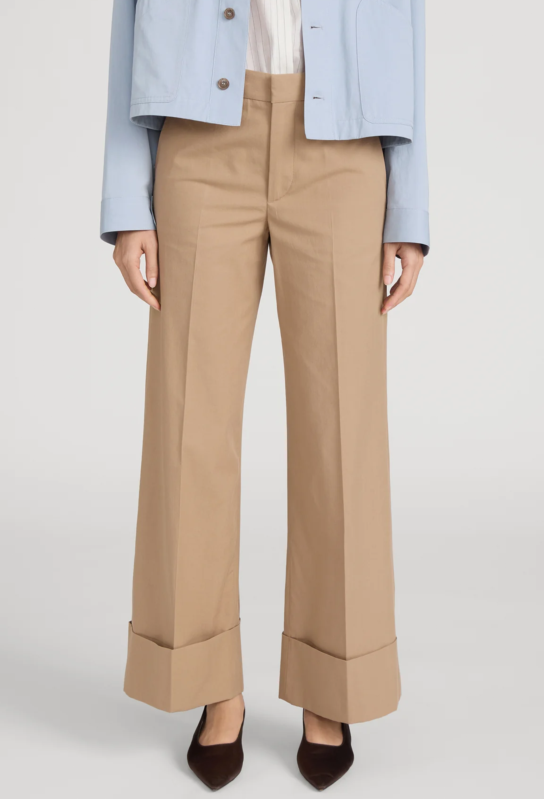 Beige pants worn with a light blue jacket on a white background