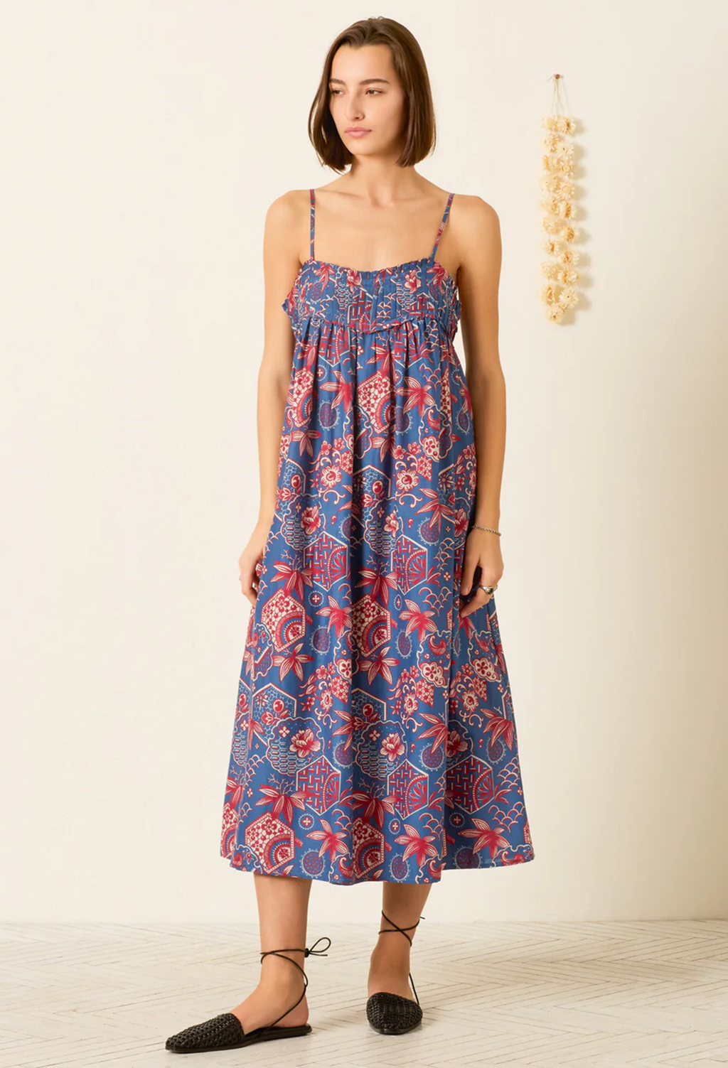 Woman wearing a blue floral dress against a plain background