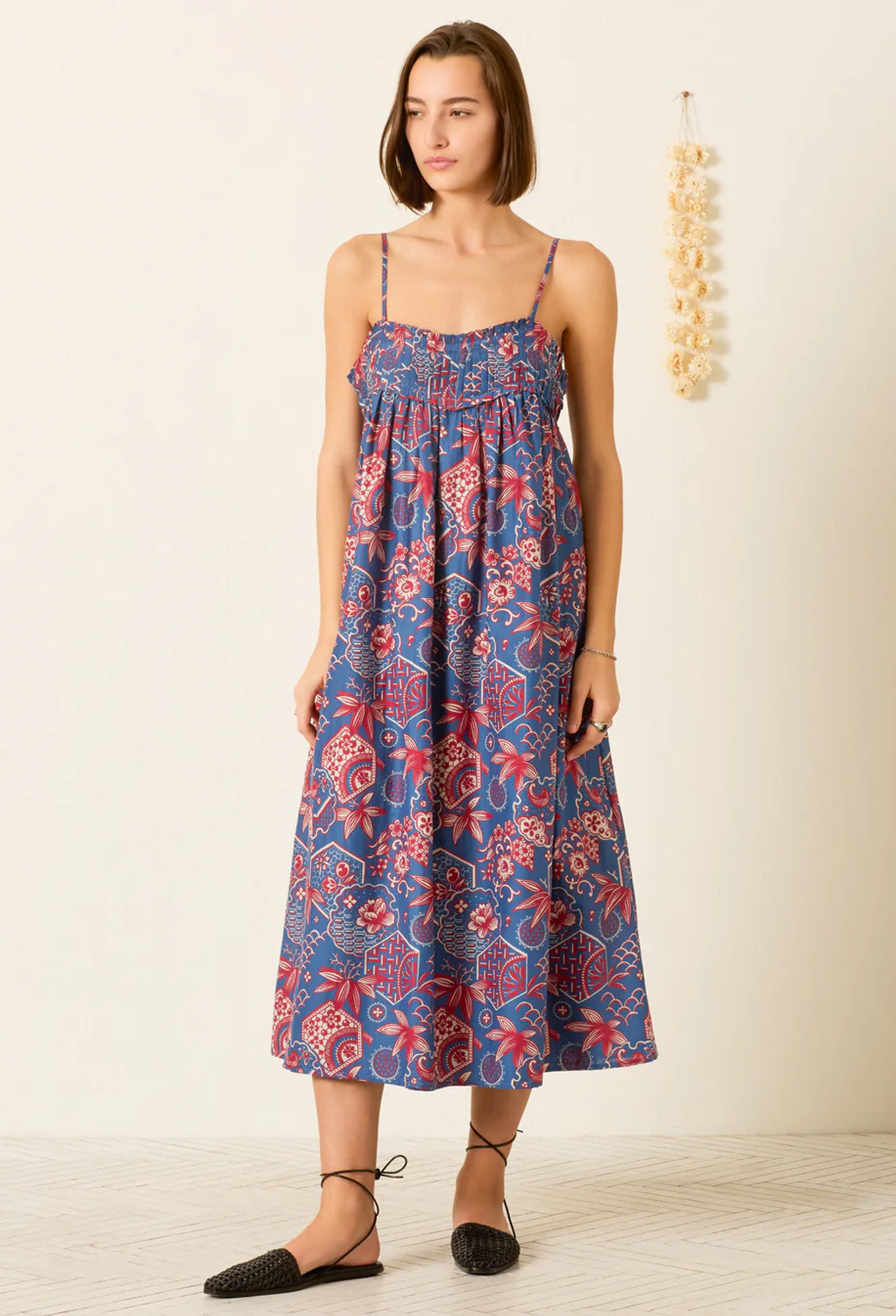 Woman wearing a blue floral dress against a plain background