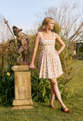 Woman in a floral dress standing next to a statue in a garden