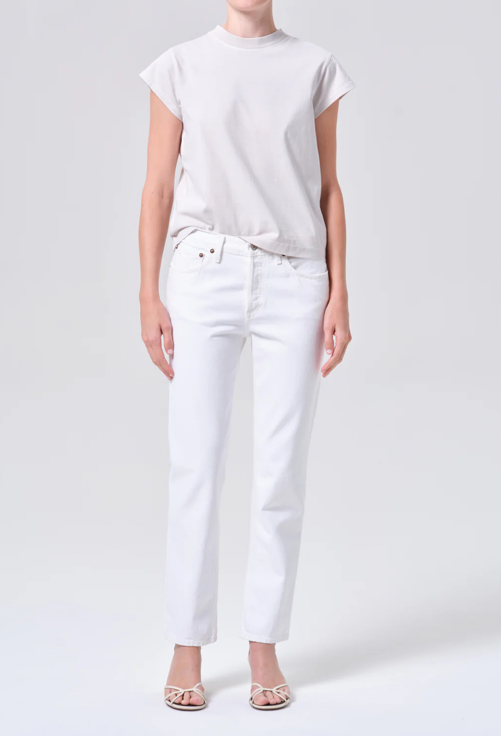Person wearing a white t-shirt and white pants on a light gray background