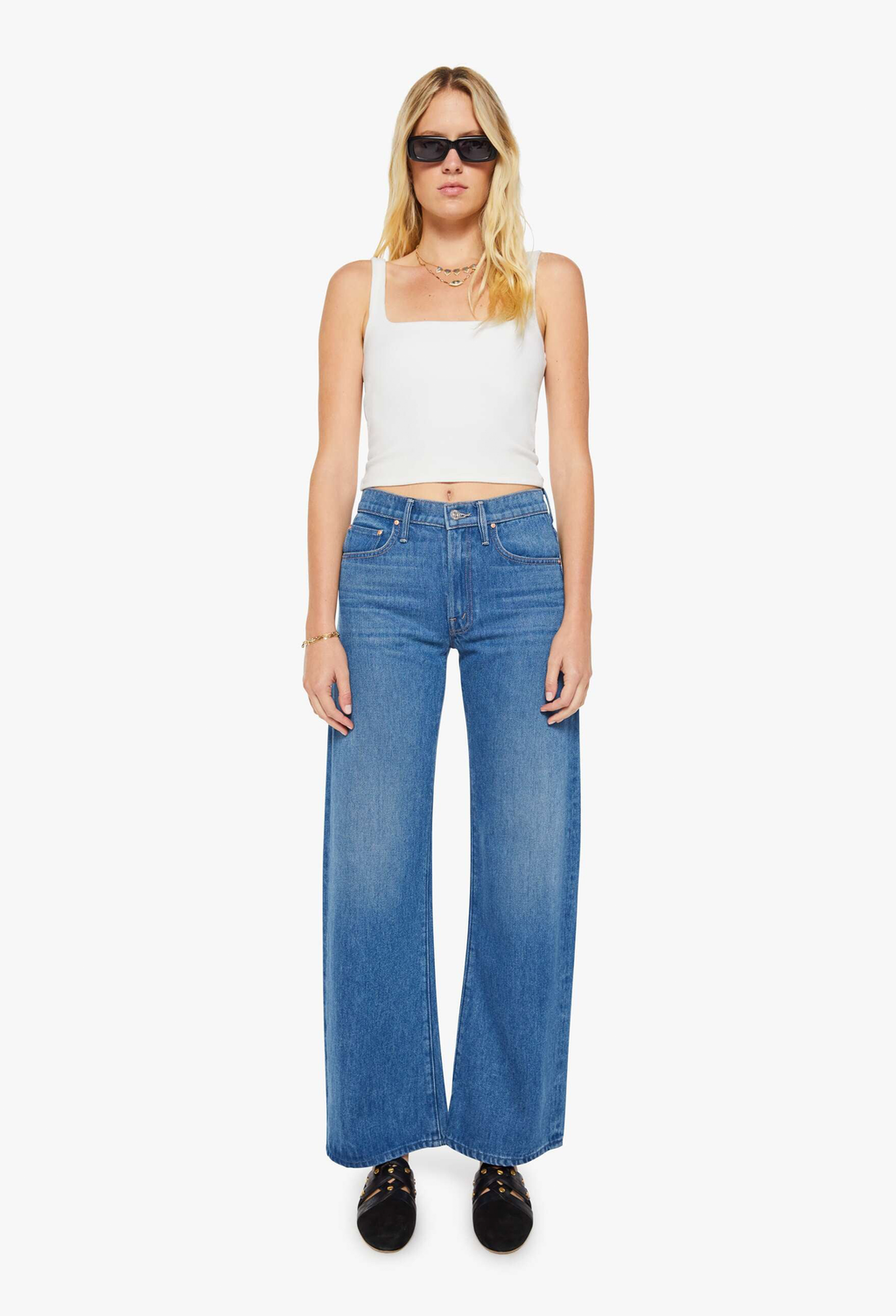 Woman wearing a white tank top and blue jeans on a white background