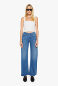 Woman wearing a white tank top and blue jeans on a white background