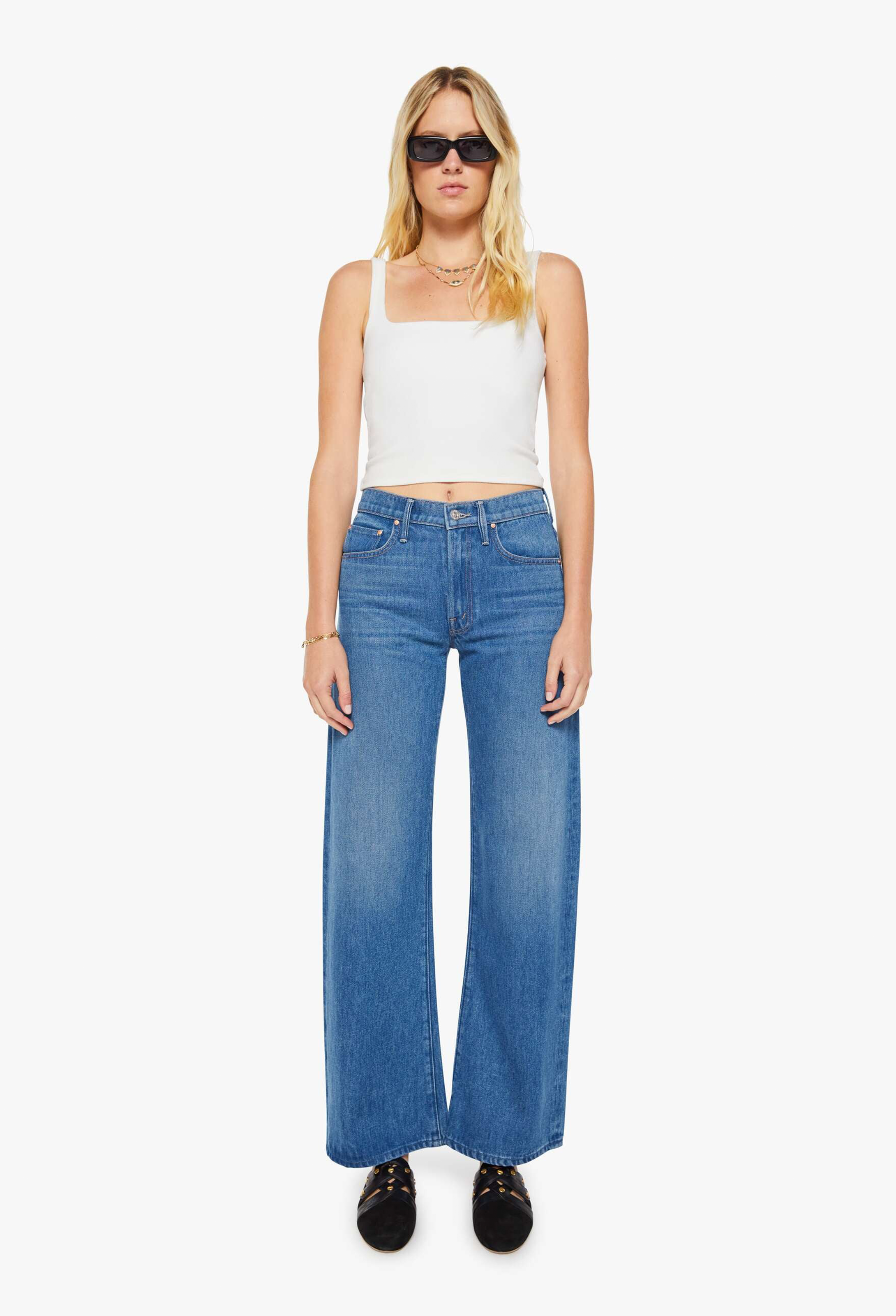 Woman wearing a white tank top and blue jeans on a white background