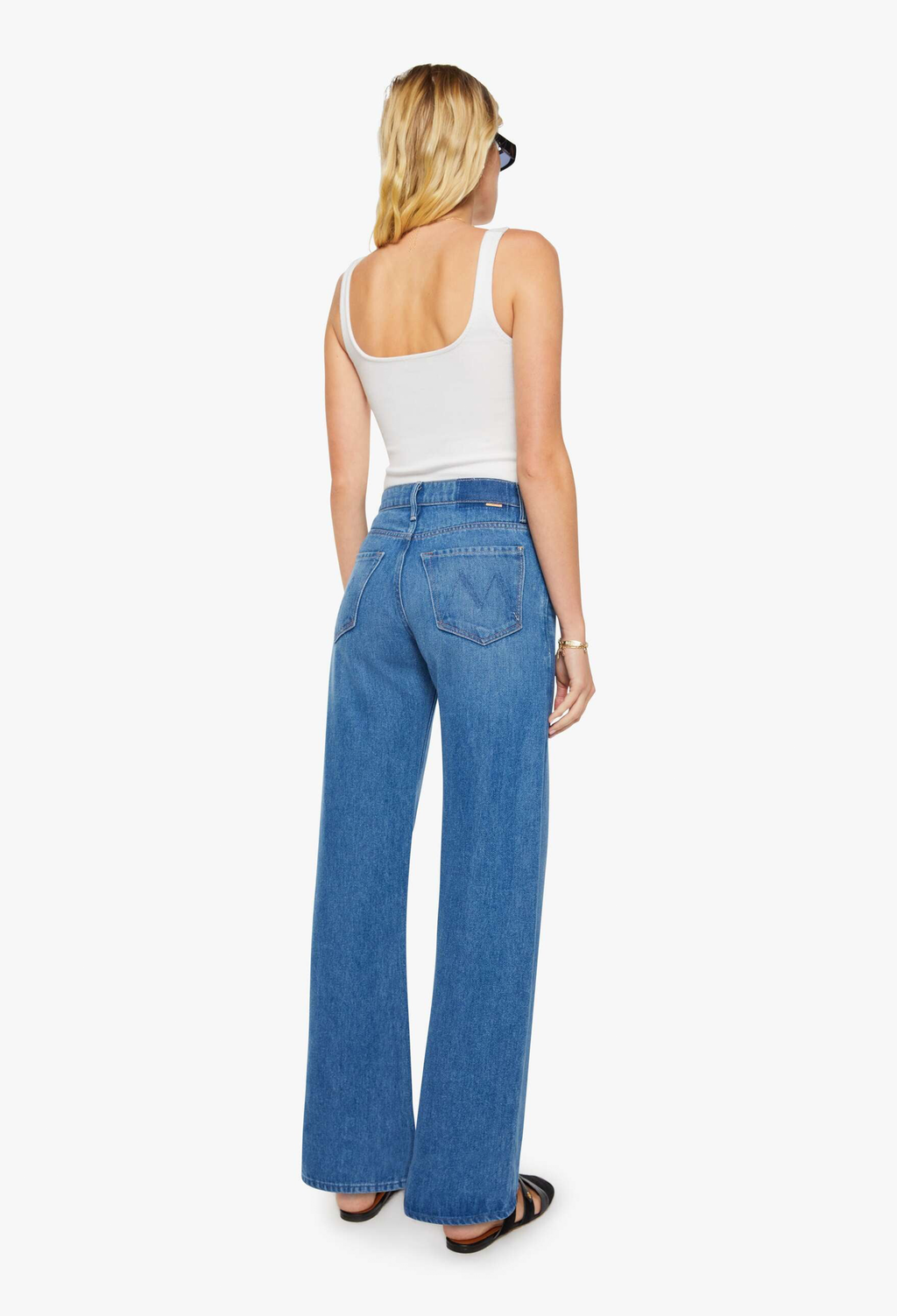 Woman wearing blue jeans and a white tank top on a white background