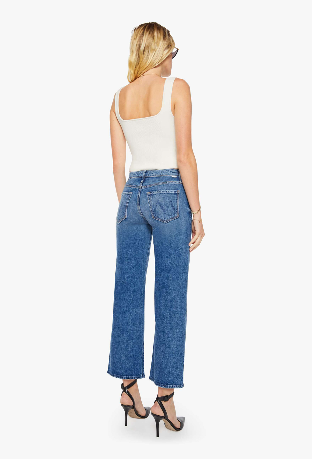 Woman wearing blue jeans and a white top on a white background