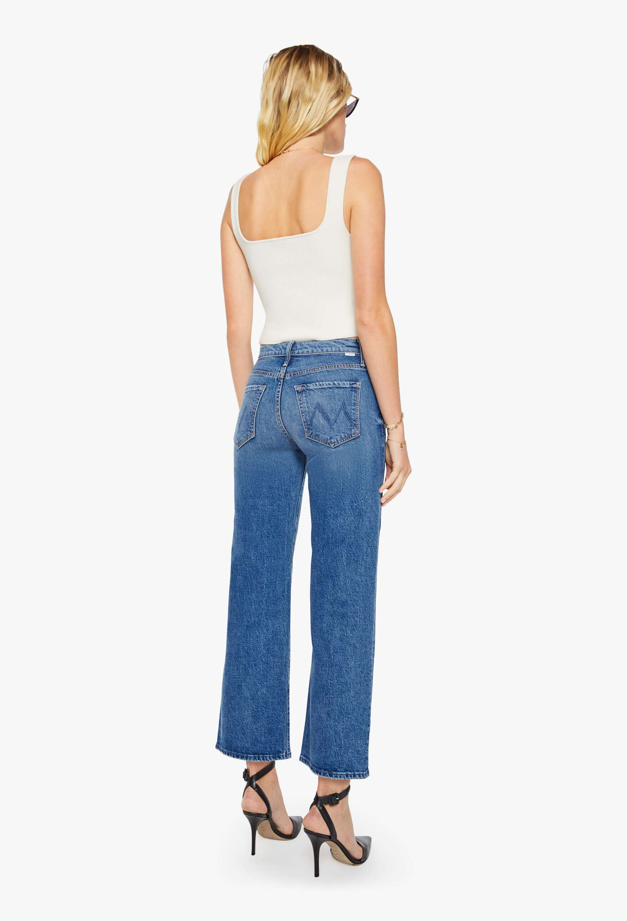 Woman wearing blue jeans and a white top on a white background
