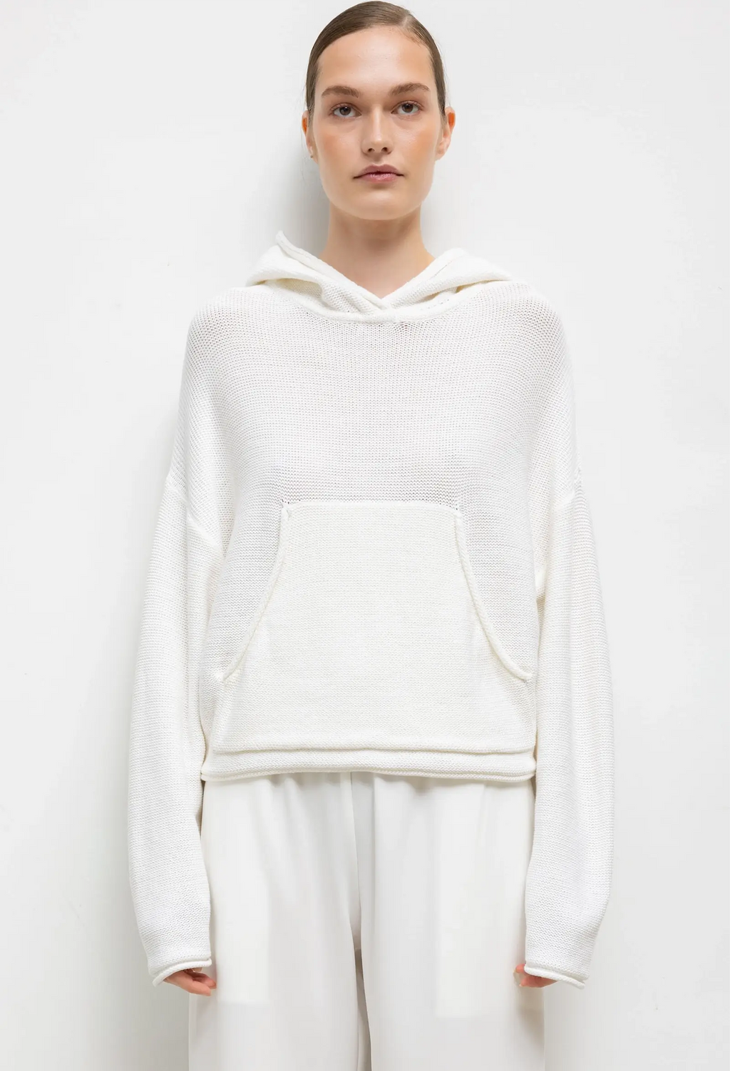 Person wearing a white hoodie and pants on a plain background