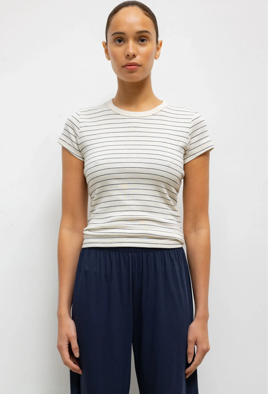 Woman wearing a striped shirt and navy pants against a white background