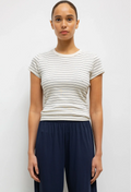 Woman wearing a striped shirt and navy pants against a white background
