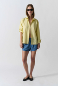 Woman wearing a yellow shirt and blue striped shorts on a white background