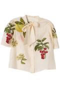 An off-white short-sleeve button-up shirt featuring colorful embroidered fruit and leaf motifs, including red cherries, yellow lemons, and green leaves, with a large bow tie at the collar.