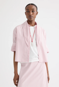 A model wearing a red and white vertically striped cropped shirt with a tie neck, paired with a white t-shirt and a matching skirt, set against a plain white studio background.