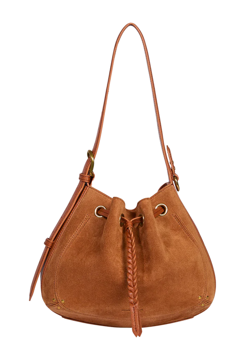 A tan suede drawstring bucket bag with a single shoulder strap, gold-tone hardware, and a braided leather tassel, shown against a plain white background.