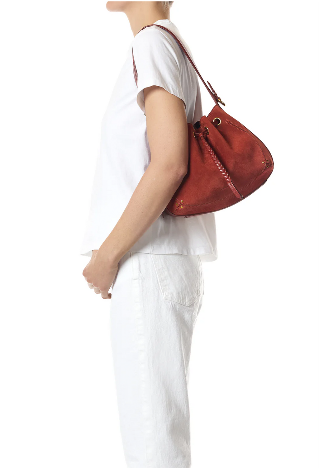 A person in a white t-shirt and white pants shown from the side, wearing a reddish-brown suede shoulder bag with a drawstring closure.