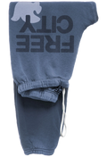 A pair of faded blue sweatpants featuring a large dark gray 'FREE CITY' graphic and a white dove on the leg, with a white drawstring at the ankle.
