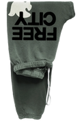 Dark olive green sweatpants featuring a large black 'FREE CITY' text graphic and a white dove logo on the upper leg, with a white drawstring at the ankle.