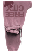 A pair of faded dusty rose sweatpants featuring a large tonal 'FREE CITY' graphic with a bear silhouette on the leg, shown folded on a white background.