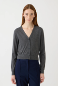 A woman modeling a dark gray button-up cardigan sweater with a V-neck, paired with navy blue trousers, against a plain light gray studio background.