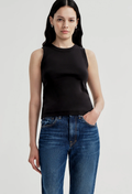 A woman modeling a black sleeveless ribbed knit top paired with blue jeans, photographed against a light gray studio background.