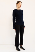 A woman modeling a dark navy blue long-sleeve knit sweater and black wide-leg trousers against a plain white studio background.