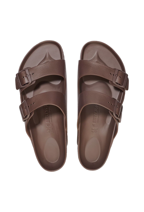 A pair of all-brown two strap buckle sandals. Transparent background