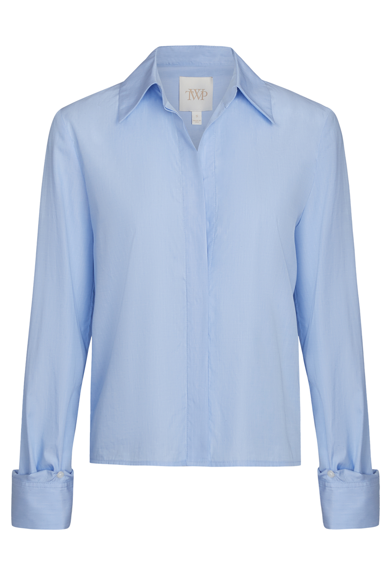 A slightly cropped light blue button down shirt with a covered placket. Transparent background.