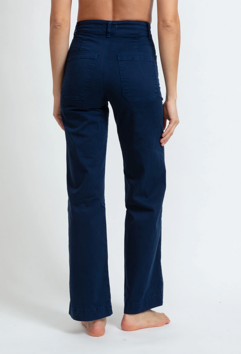 The back of a woman wearing dark blue pants with large front pockets. White background.