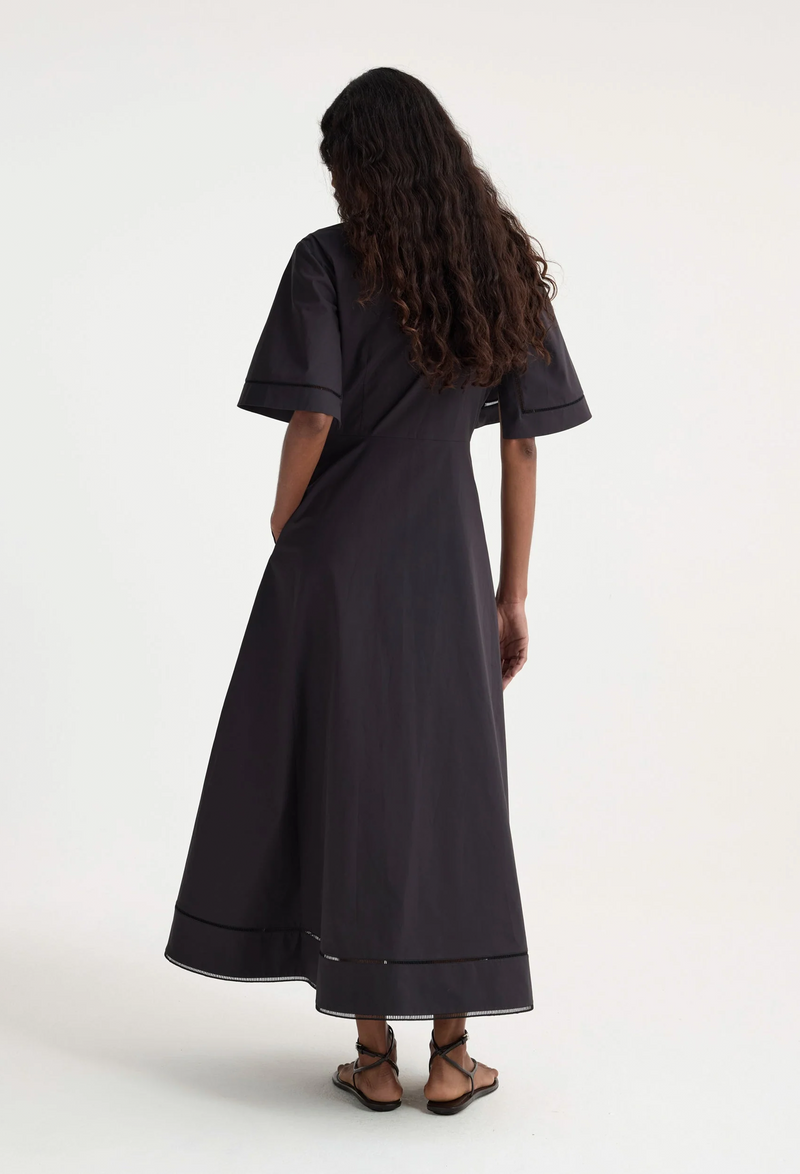 The back of a woman wearing a collared black short sleeve midi dress. Transparent background.