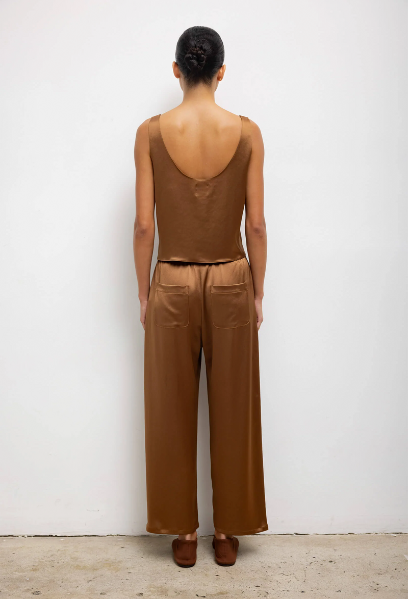The back of a woman wearing a loose brown tank top and matching pants. White background.
