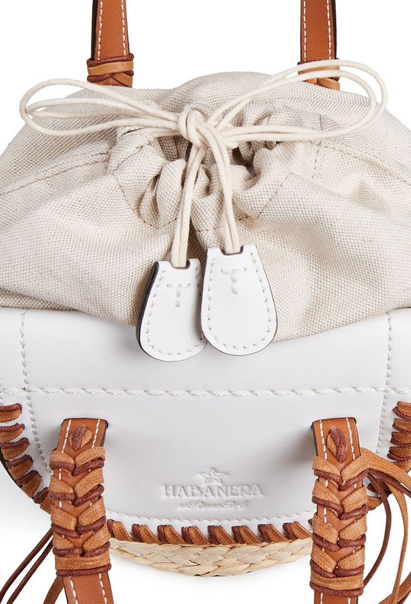 Close up of the off-white inner lining drawstring bag of a mini basket bag with white leather flaps and brown cord detailing.